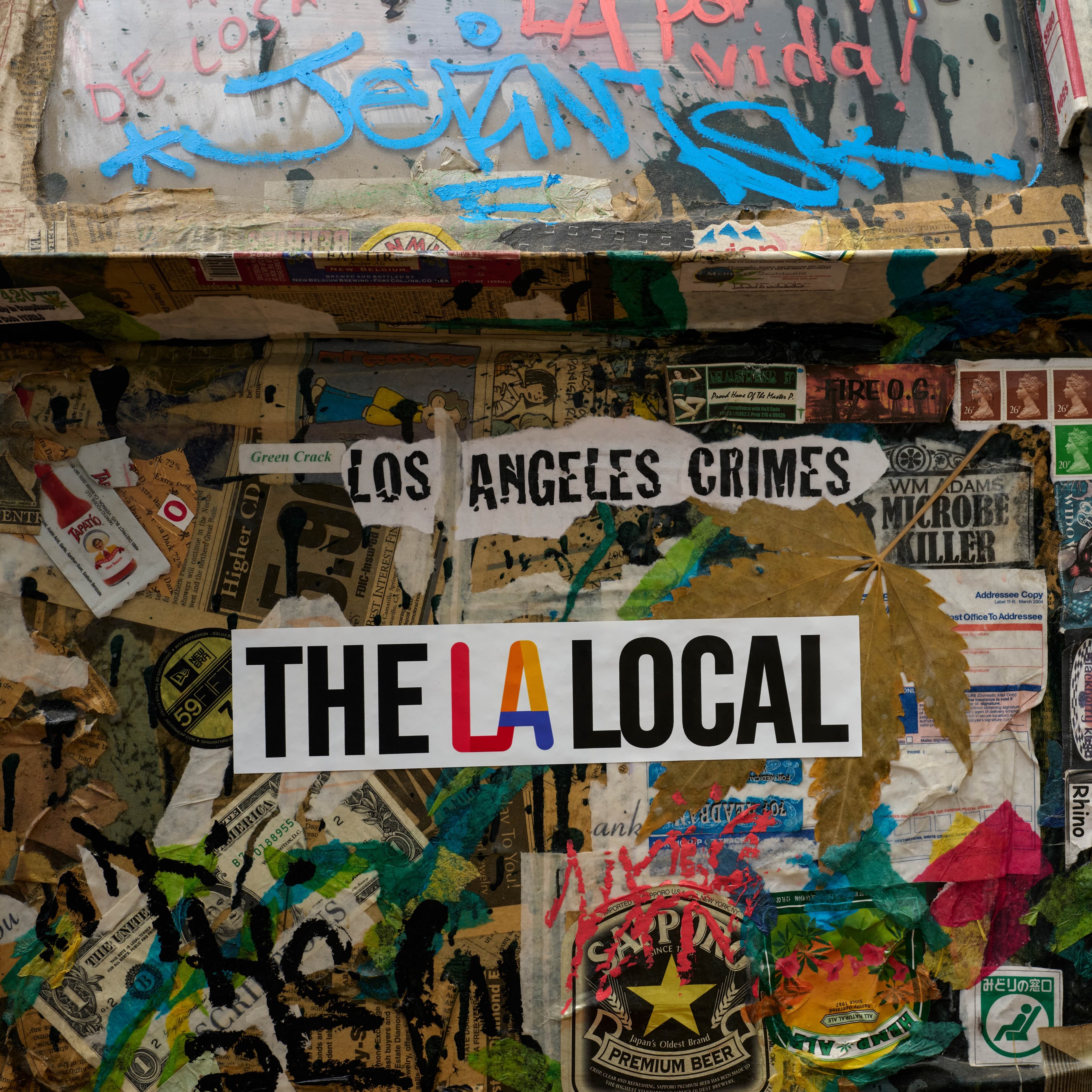 A sticker reading “The LA Local” on a surface covered in layered stickers, posters, and graffiti.